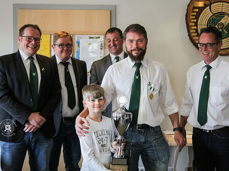 Der stolze Vereinsmeister Marcus Braun nimmt gemeinsam mit seinem Sohn den Pokal durch die Vorstandmitglieder entgegen.